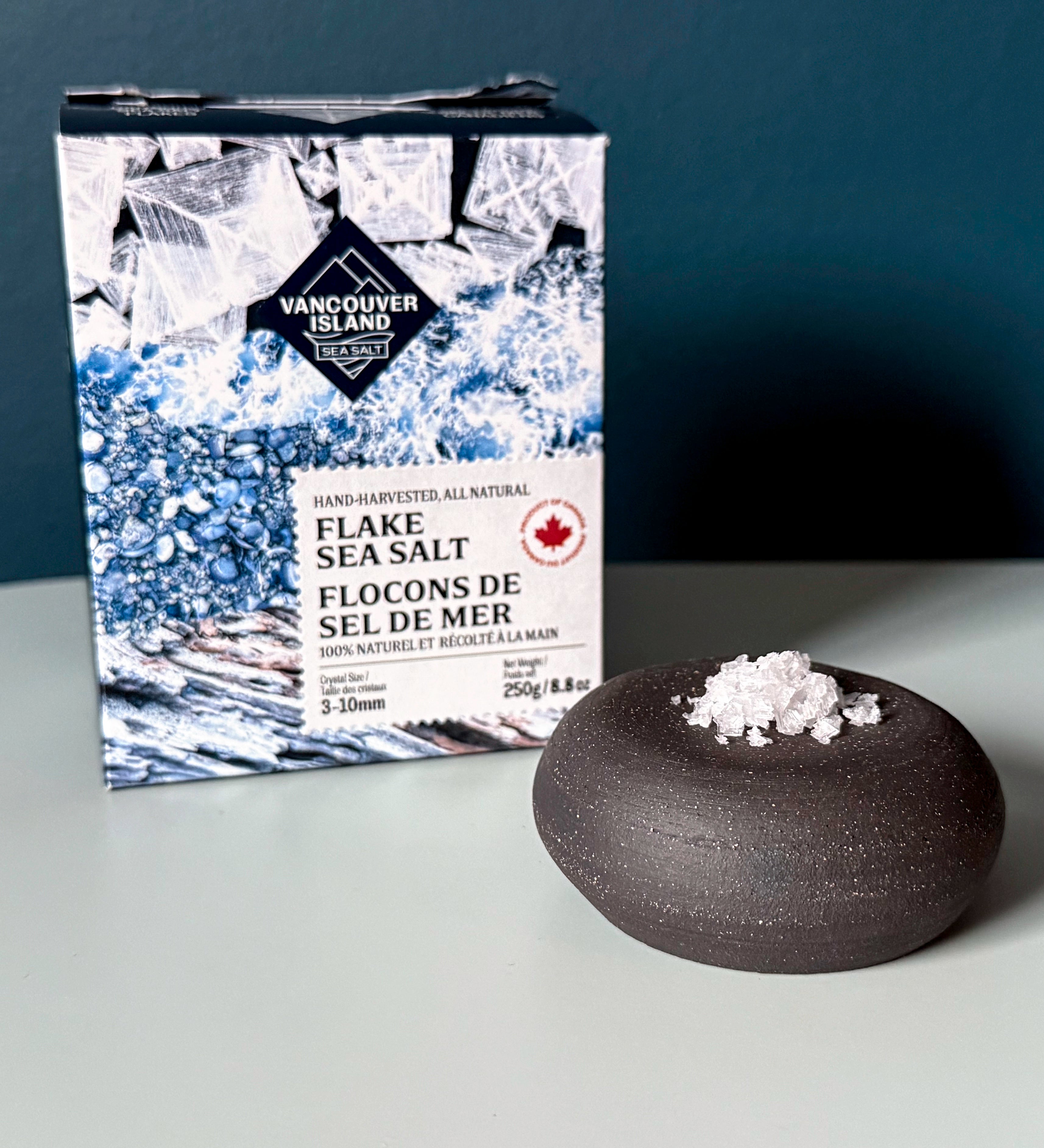 Vancouver Island Flake Sea Salt packaging with a small bowl of salt on a gray background